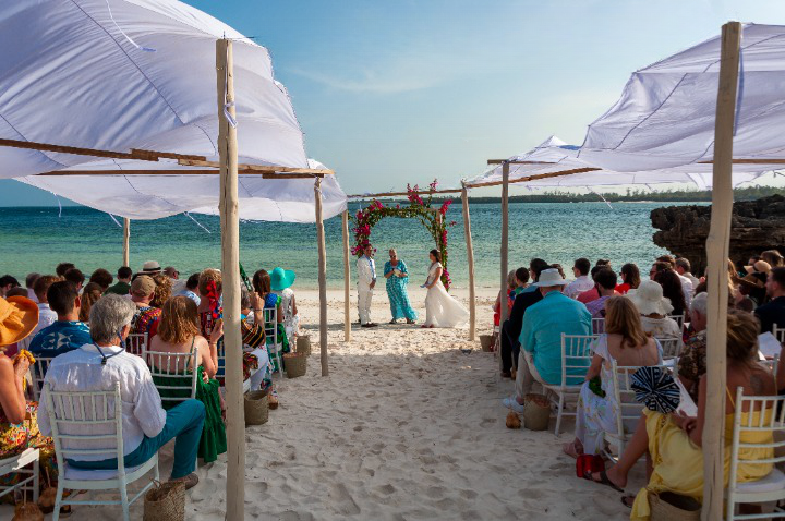 Trauzeremonie am Meer mit Gästen unter weißen Sonnensegeln bei einer Hochzeit in Kenia – emotionale Momente beim Heiraten in Kenia und Inspiration für die Hochzeitsplanung.